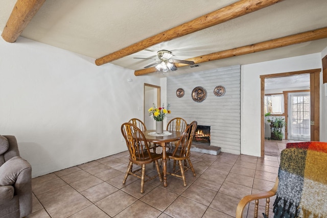 dining room with light tile patterned floors, a fireplace, visible vents, and beamed ceiling