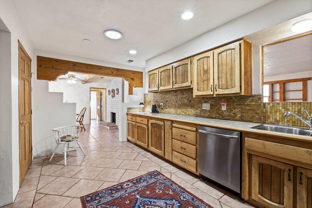 kitchen with light tile patterned floors, backsplash, stainless steel dishwasher, a brick fireplace, and a sink