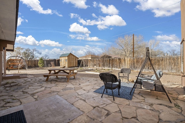 view of patio / terrace with a fenced backyard, a storage unit, and an outbuilding