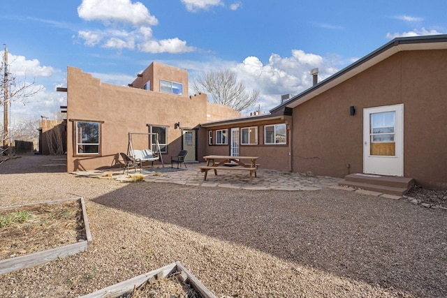 rear view of house with a garden, a patio, fence, and stucco siding