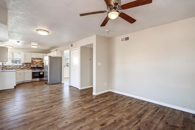 unfurnished living room with dark wood finished floors, visible vents, a sink, a textured ceiling, and baseboards