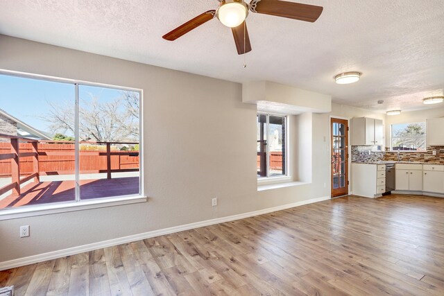 unfurnished living room with baseboards, light wood-style flooring, ceiling fan, a textured ceiling, and a sink