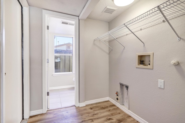 laundry area with laundry area, visible vents, hookup for a gas dryer, light wood-style flooring, and washer hookup