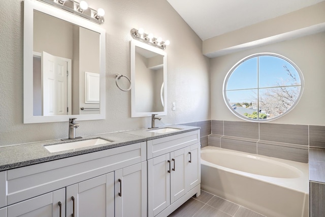 bathroom featuring a bath, tile patterned flooring, double vanity, and a sink