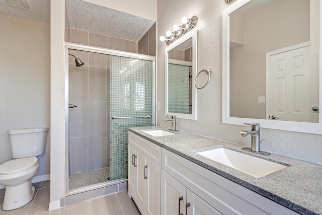 bathroom with double vanity, a stall shower, a sink, and toilet