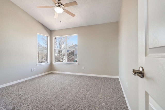 carpeted empty room featuring a ceiling fan, vaulted ceiling, a textured ceiling, and baseboards