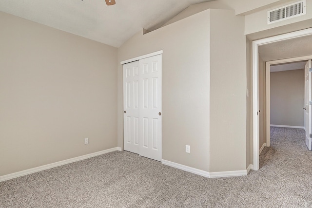 unfurnished bedroom featuring baseboards, visible vents, vaulted ceiling, and carpet flooring