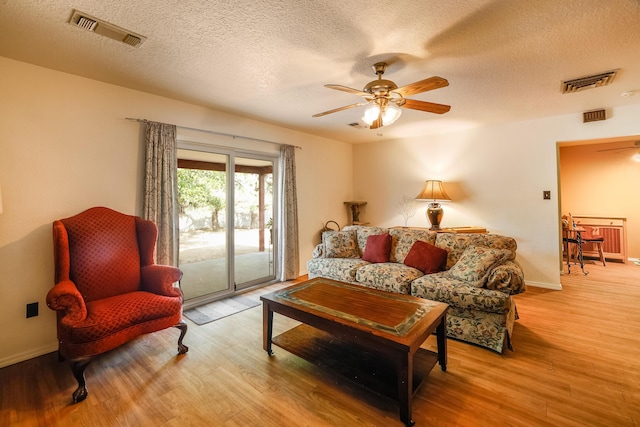 living room with a ceiling fan, visible vents, and wood finished floors