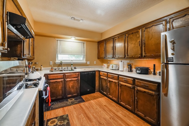 kitchen featuring a sink, visible vents, freestanding refrigerator, dishwasher, and gas stove