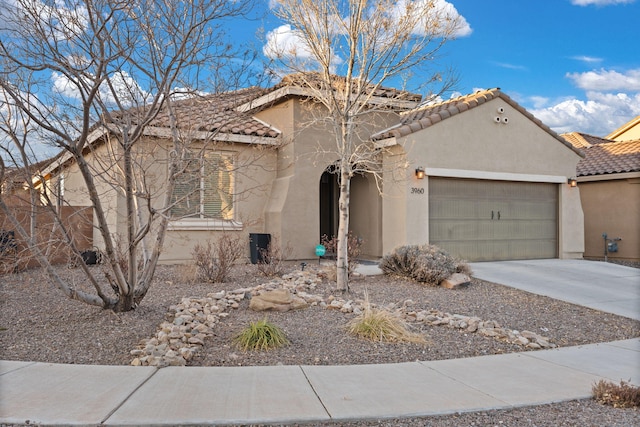 mediterranean / spanish house featuring an attached garage, driveway, a tile roof, and stucco siding