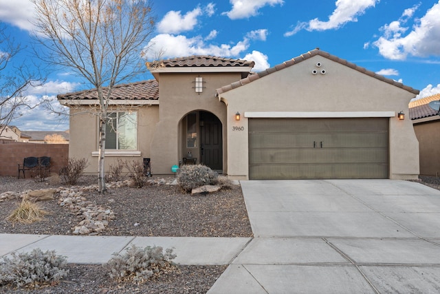 mediterranean / spanish-style home featuring a garage, driveway, a tiled roof, fence, and stucco siding