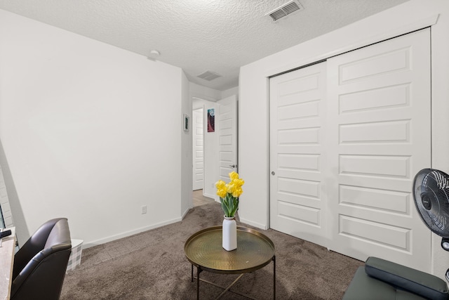 sitting room with baseboards, carpet, visible vents, and a textured ceiling