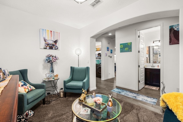 sitting room with baseboards, visible vents, arched walkways, washer / clothes dryer, and wood finished floors