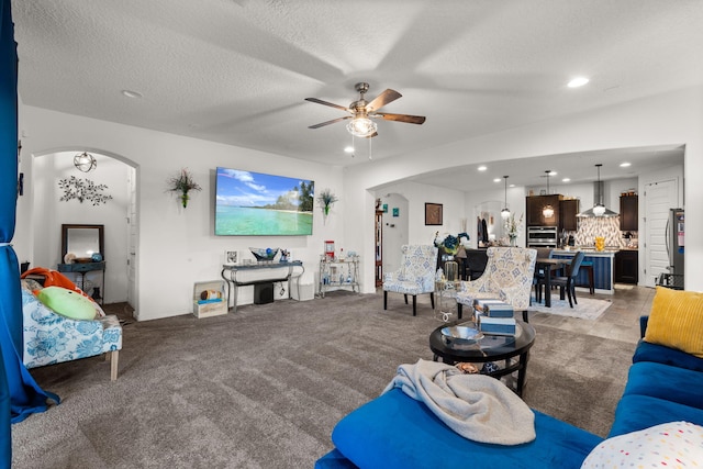 living area featuring arched walkways, ceiling fan, a textured ceiling, and recessed lighting