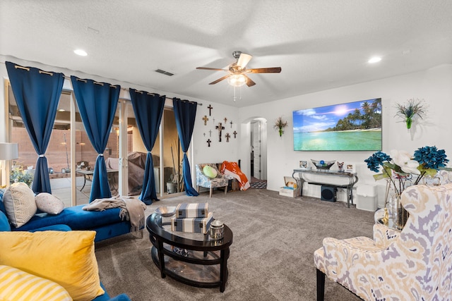 living room with arched walkways, visible vents, a ceiling fan, carpet flooring, and a textured ceiling