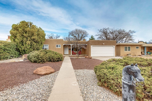 adobe home featuring an attached garage and stucco siding