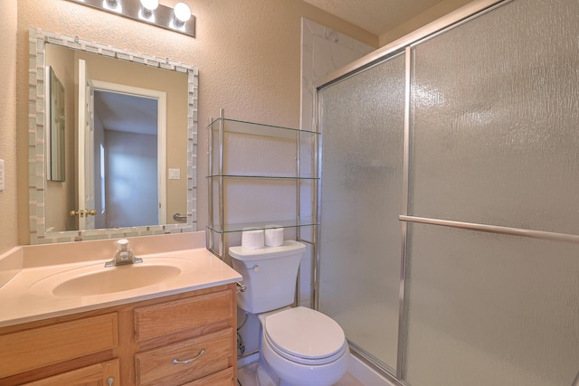 full bathroom with toilet, a textured wall, a shower stall, and vanity