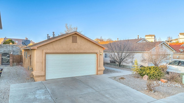 ranch-style house with stucco siding, an attached garage, a gate, fence, and driveway