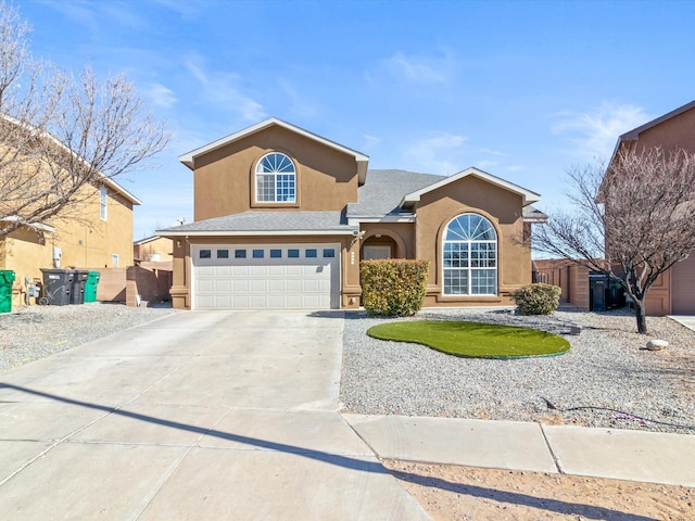 traditional-style house featuring a garage, driveway, fence, and stucco siding