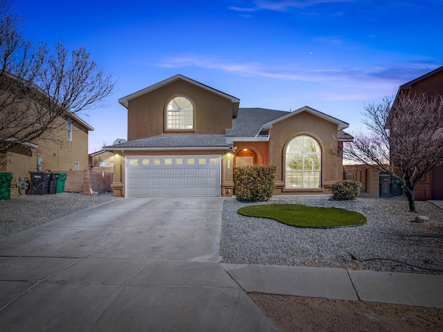 traditional-style house with an attached garage, fence, concrete driveway, and stucco siding