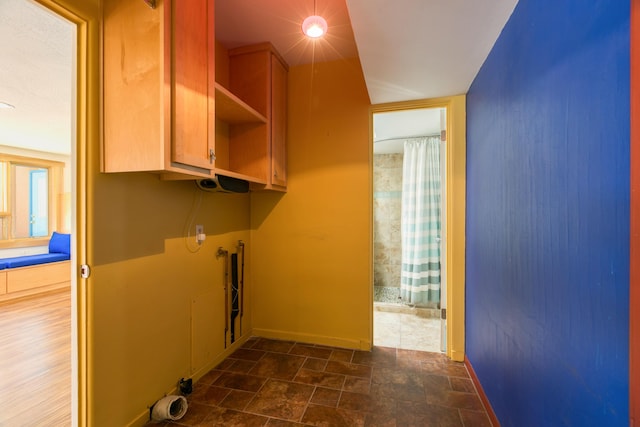 laundry room with stone finish floor, laundry area, and baseboards