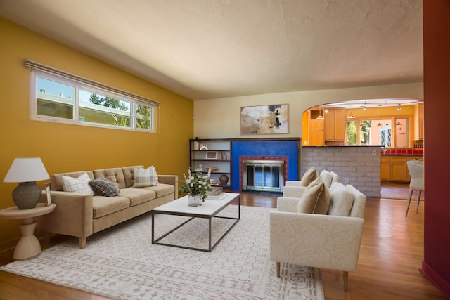 living room featuring a textured ceiling, a glass covered fireplace, and wood finished floors