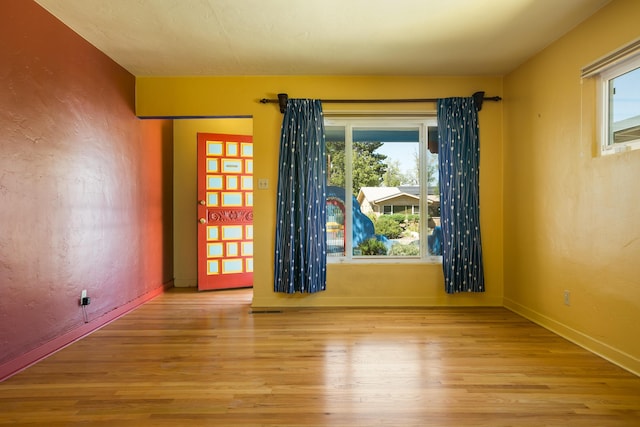 unfurnished room with a textured wall, baseboards, and wood finished floors