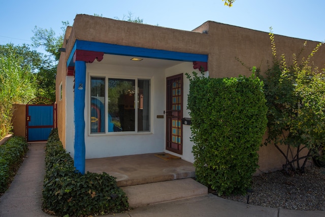 doorway to property featuring a gate and stucco siding