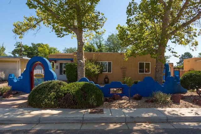 pueblo revival-style home with fence and stucco siding