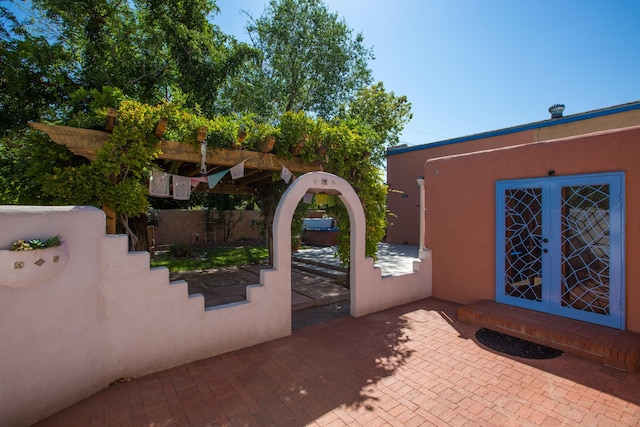 doorway to property with french doors, a patio area, fence, and stucco siding