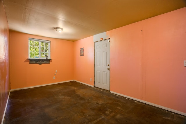 unfurnished room featuring concrete flooring and baseboards