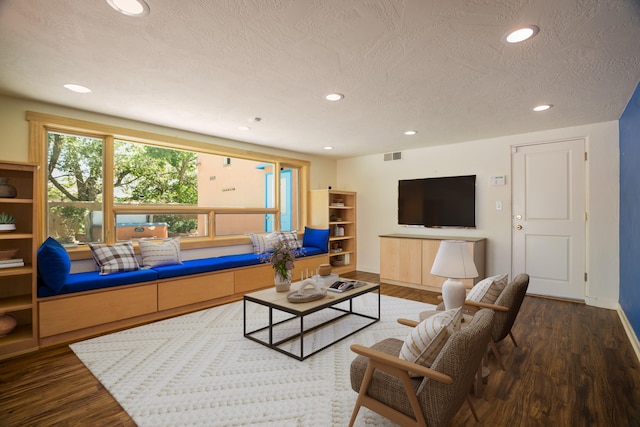 living room featuring a textured ceiling, visible vents, wood finished floors, and recessed lighting