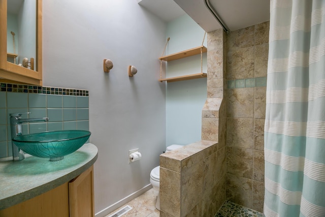 bathroom with visible vents, toilet, a tile shower, vanity, and baseboards