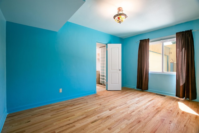 unfurnished bedroom with wood finished floors, visible vents, and baseboards