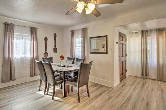 dining room featuring baseboards, ceiling fan, a textured ceiling, and light wood finished floors