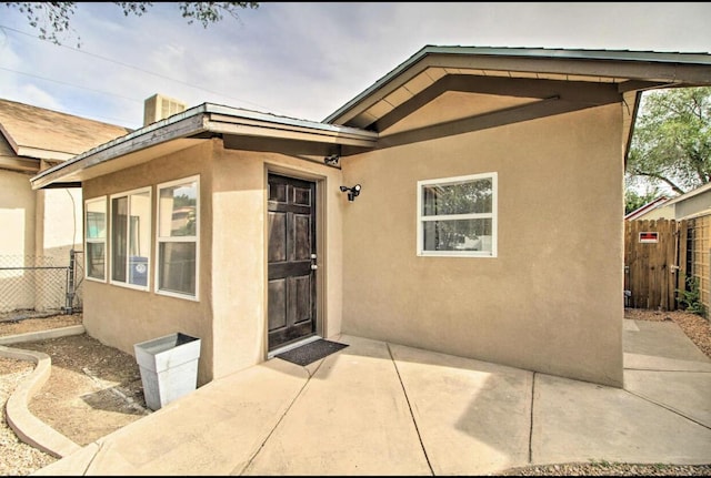 doorway to property featuring a patio, fence, and stucco siding