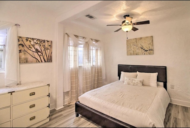 bedroom with visible vents, a ceiling fan, light wood-style flooring, and baseboards