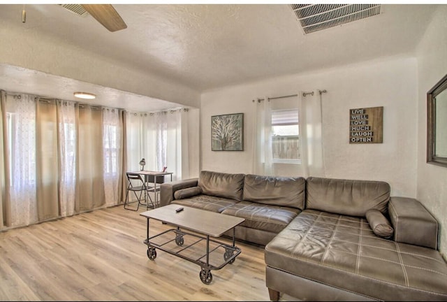 living area with a textured ceiling, wood finished floors, and visible vents