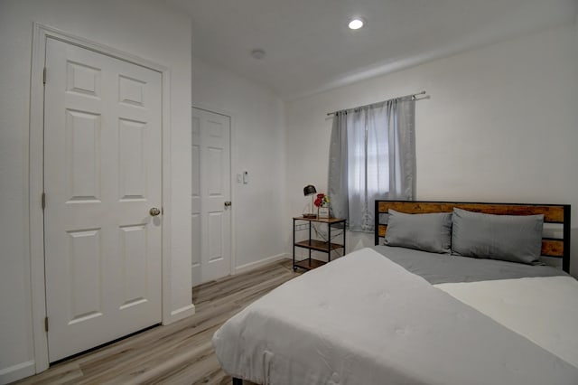 bedroom with light wood finished floors, recessed lighting, and baseboards