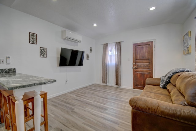 living room featuring baseboards, a wall unit AC, light wood-style flooring, a textured ceiling, and recessed lighting