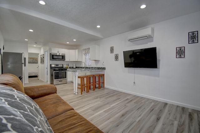 living area with an AC wall unit, light wood finished floors, recessed lighting, and baseboards