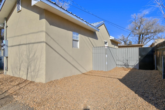 view of home's exterior featuring fence, metal roof, and stucco siding