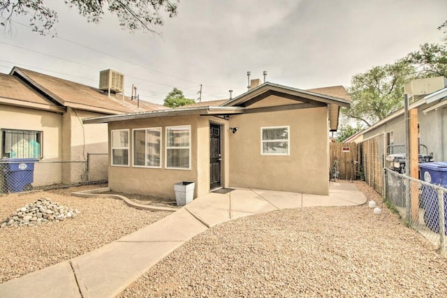 view of front facade with central AC, a patio area, a fenced backyard, and stucco siding