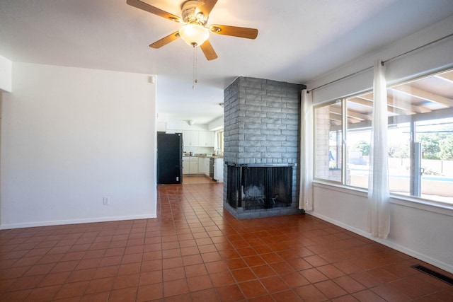 unfurnished living room featuring a fireplace, ceiling fan, visible vents, and dark tile patterned flooring