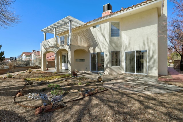 rear view of property with a balcony, a patio area, a tiled roof, and stucco siding