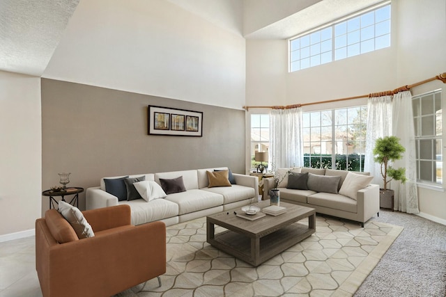 living room featuring a healthy amount of sunlight, a towering ceiling, and baseboards