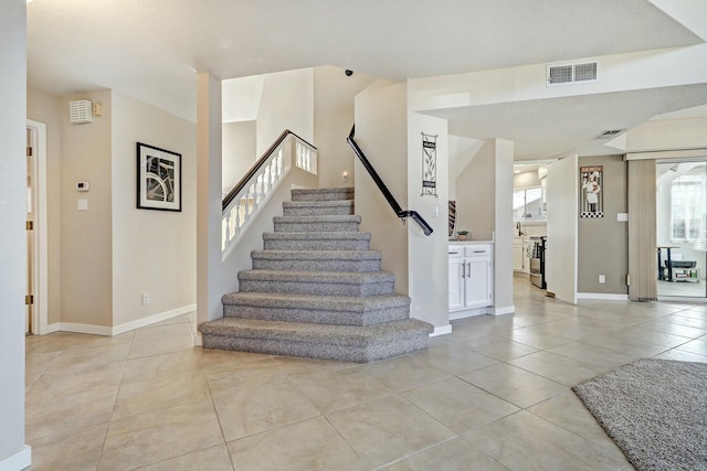 staircase featuring tile patterned flooring, visible vents, and baseboards