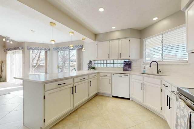 kitchen featuring a peninsula, a sink, decorative backsplash, dishwasher, and plenty of natural light