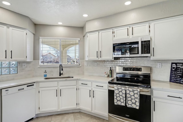 kitchen with light tile patterned floors, stainless steel appliances, decorative backsplash, white cabinetry, and a sink