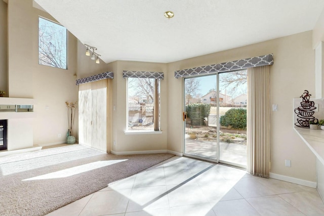 doorway featuring tile patterned floors, carpet, baseboards, and a glass covered fireplace